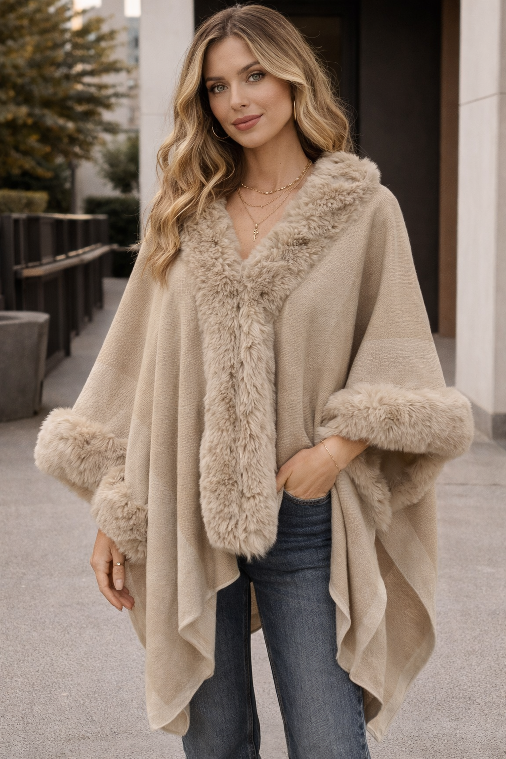Woman wearing a beige fur-trimmed poncho outdoors