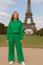 Person in a green outfit standing in front of the Eiffel Tower
