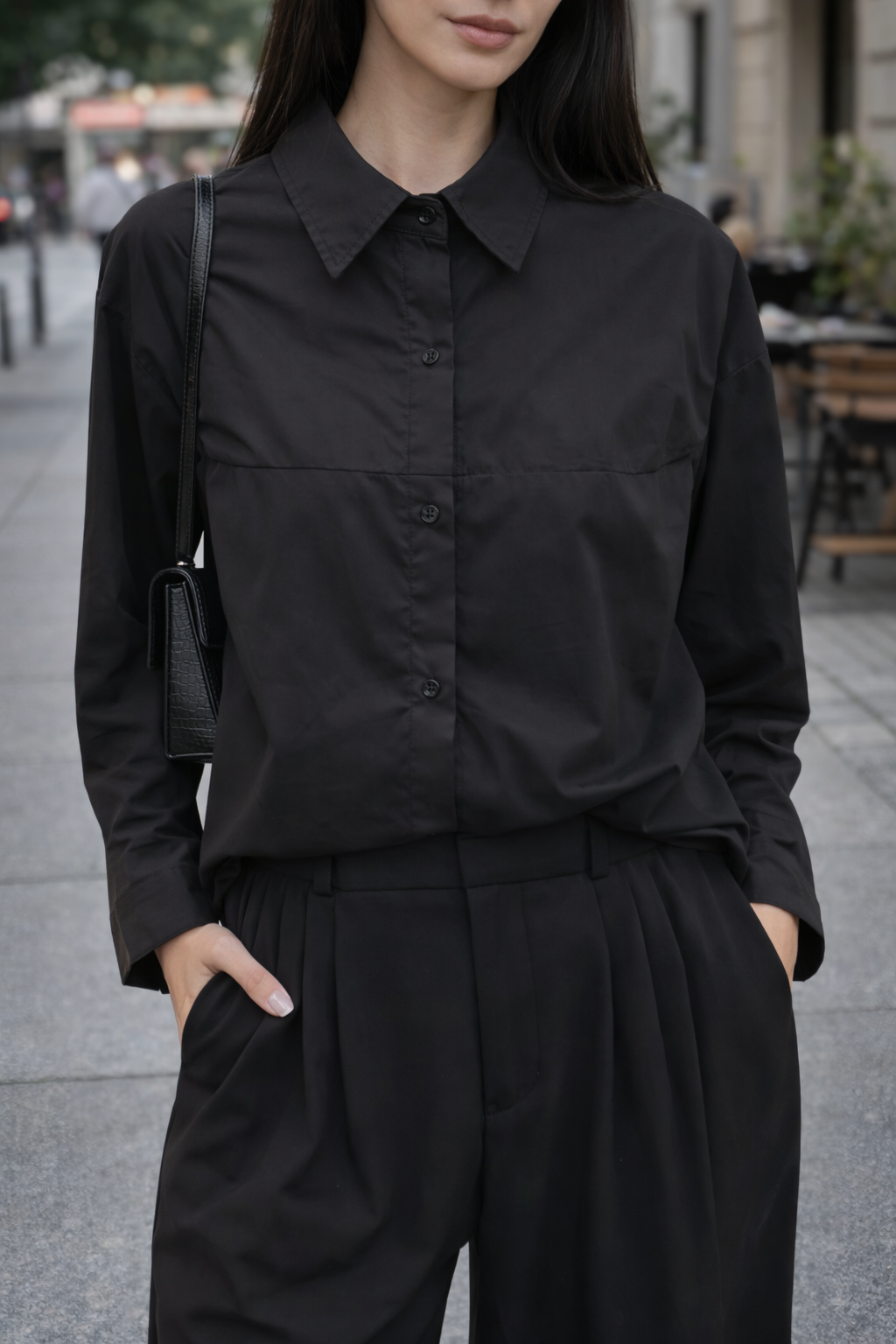 Person wearing a black outfit with a blurred urban background