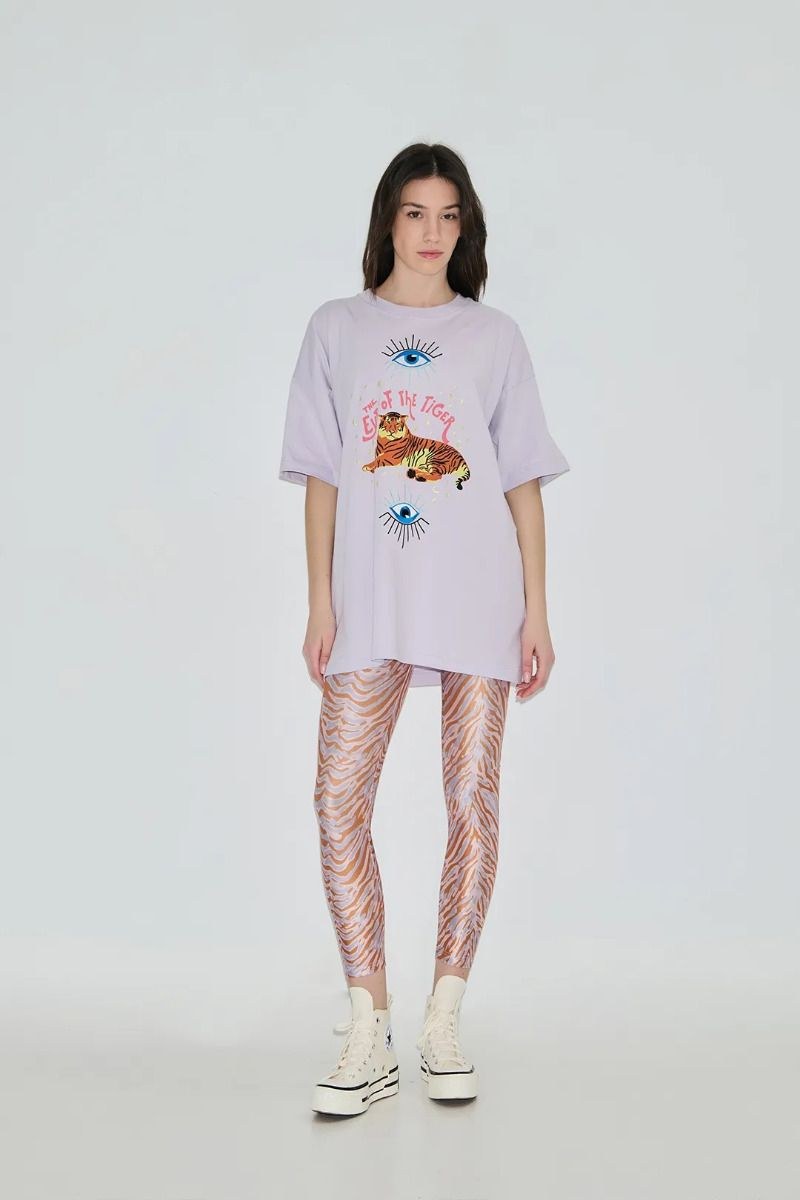 Person wearing a light purple oversized t-shirt with graphics and patterned leggings on a white background