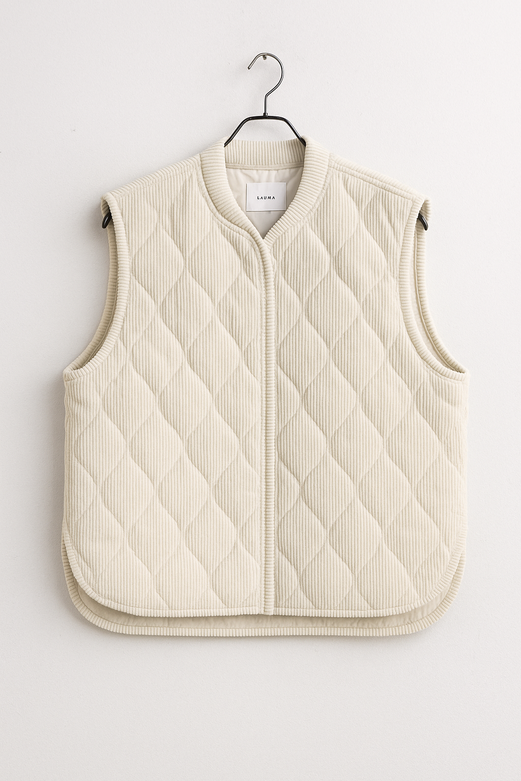 Quilted vest on a hanger against a white background