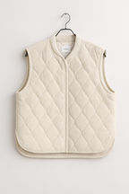 Quilted vest on a hanger against a white background