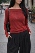 Woman wearing a red sweater and black pants on a city street.