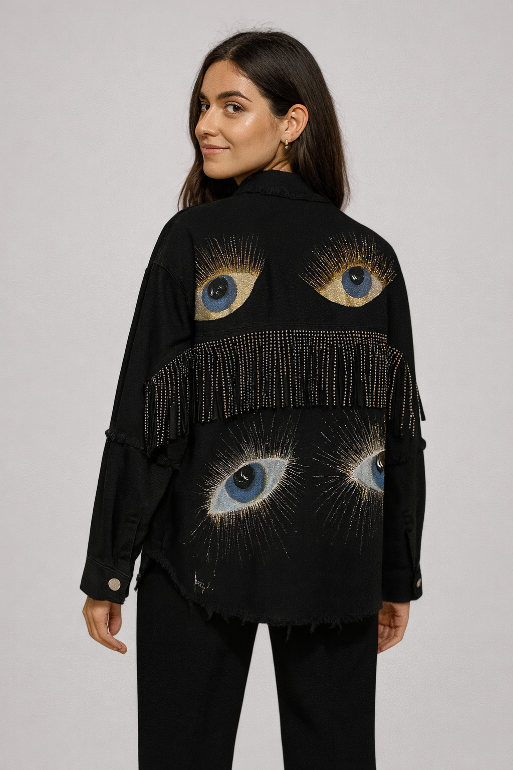 Woman wearing a black jacket with eye designs on a plain background