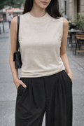 Woman wearing a beige sleeveless top and black pants on a city street.