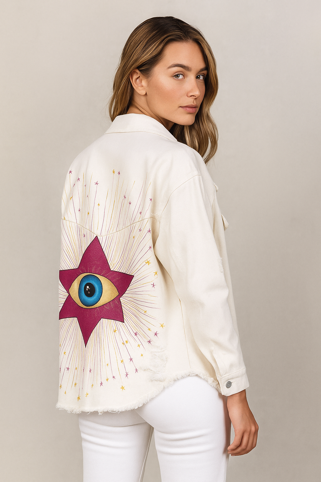 Woman wearing a white blouse with a colorful eye design on the back against a beige background