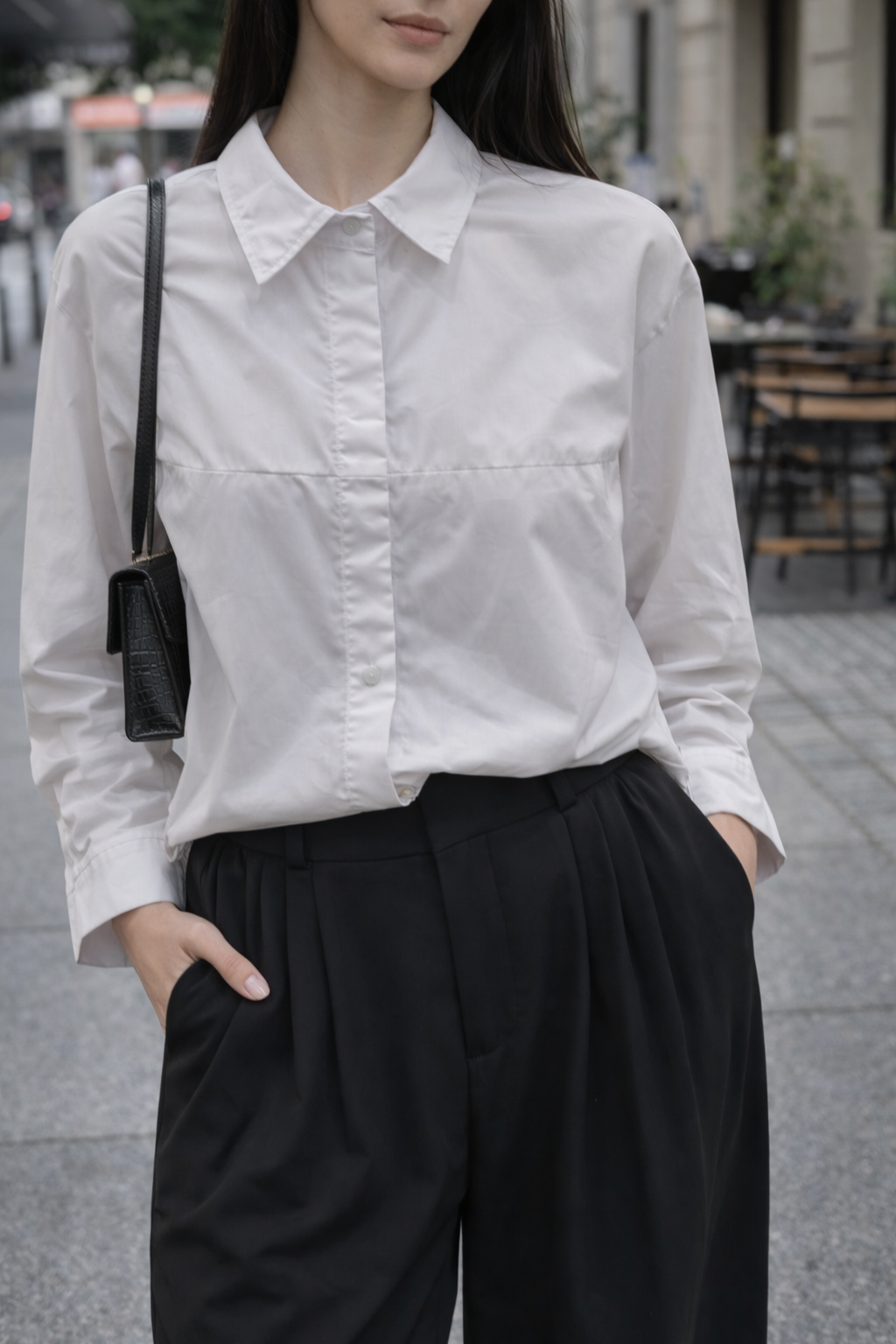 Person wearing a white shirt and black pants with a blurred background