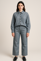 Person wearing a blue denim shirt and pants on a beige background