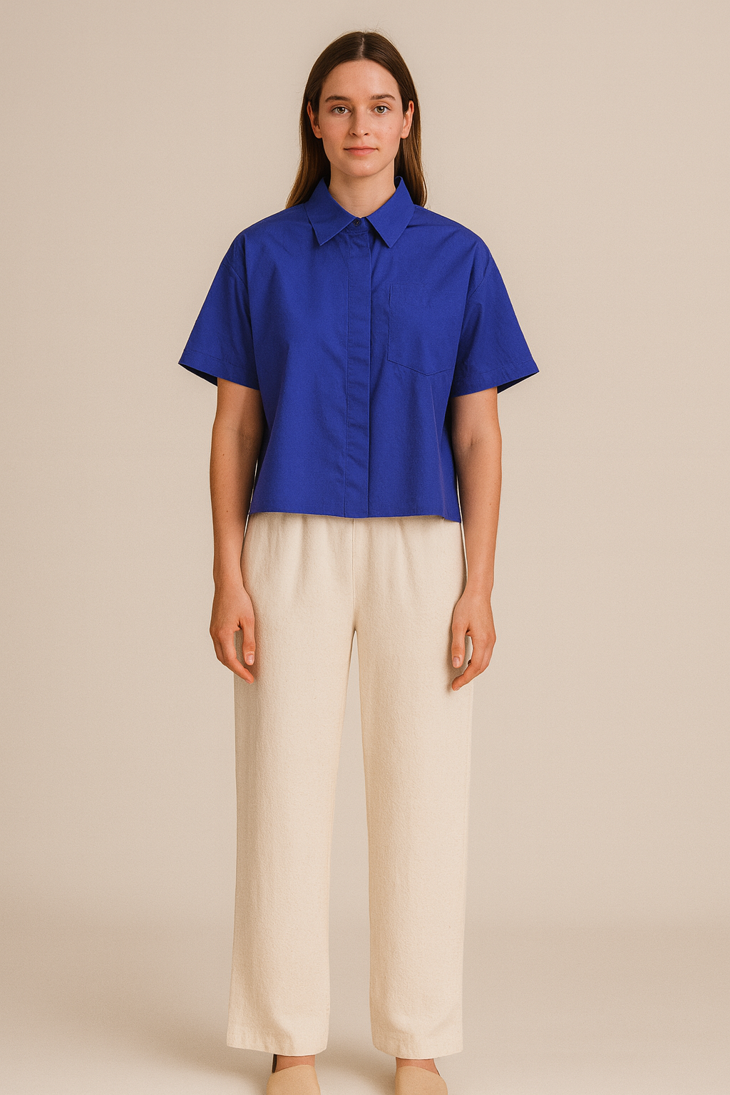 Woman wearing a blue shirt and beige pants on a beige background