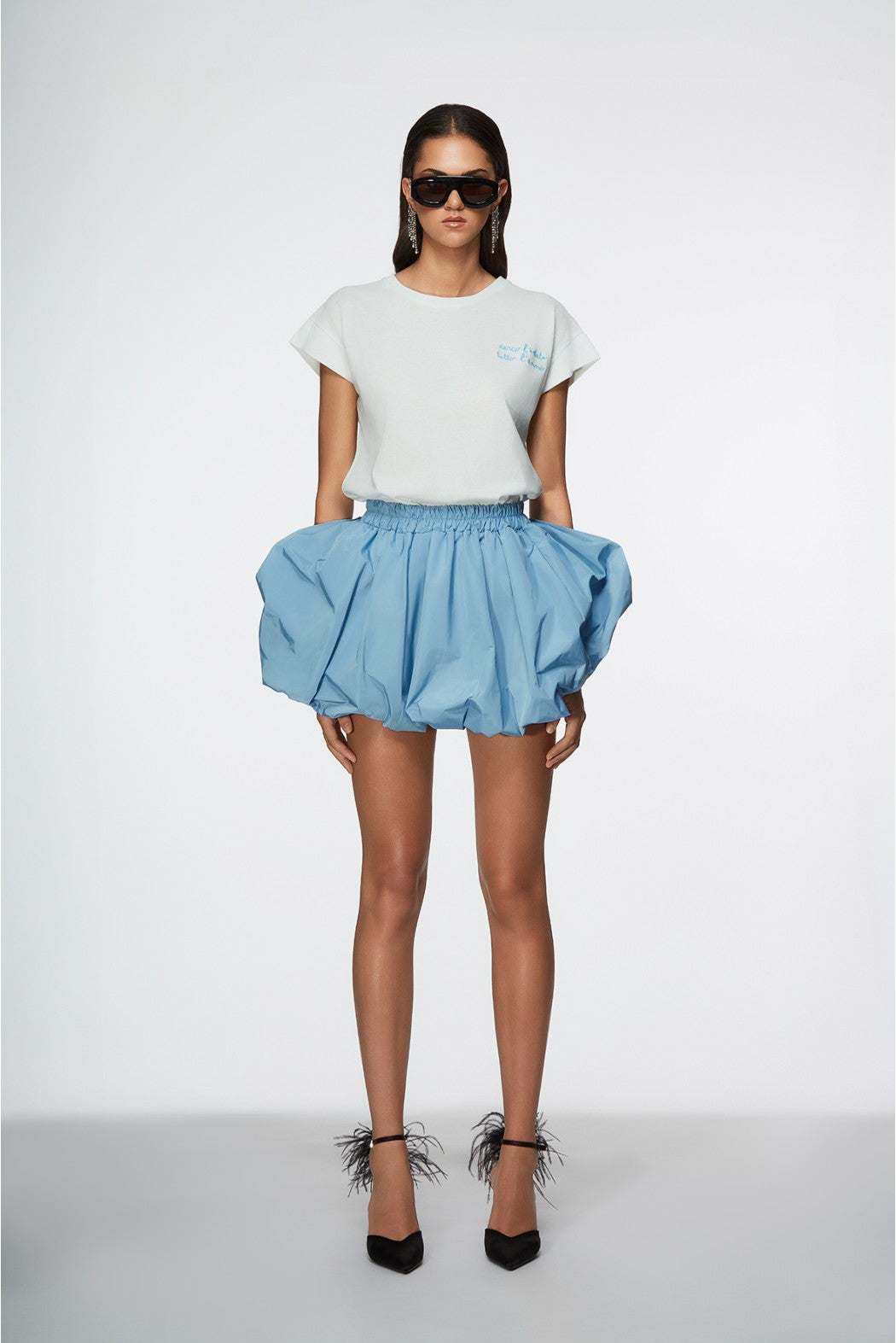 Woman wearing a white t-shirt and blue skirt on a white background