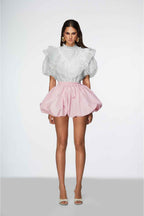 Woman wearing a white blouse with puffed sleeves and a pink skirt on a white background