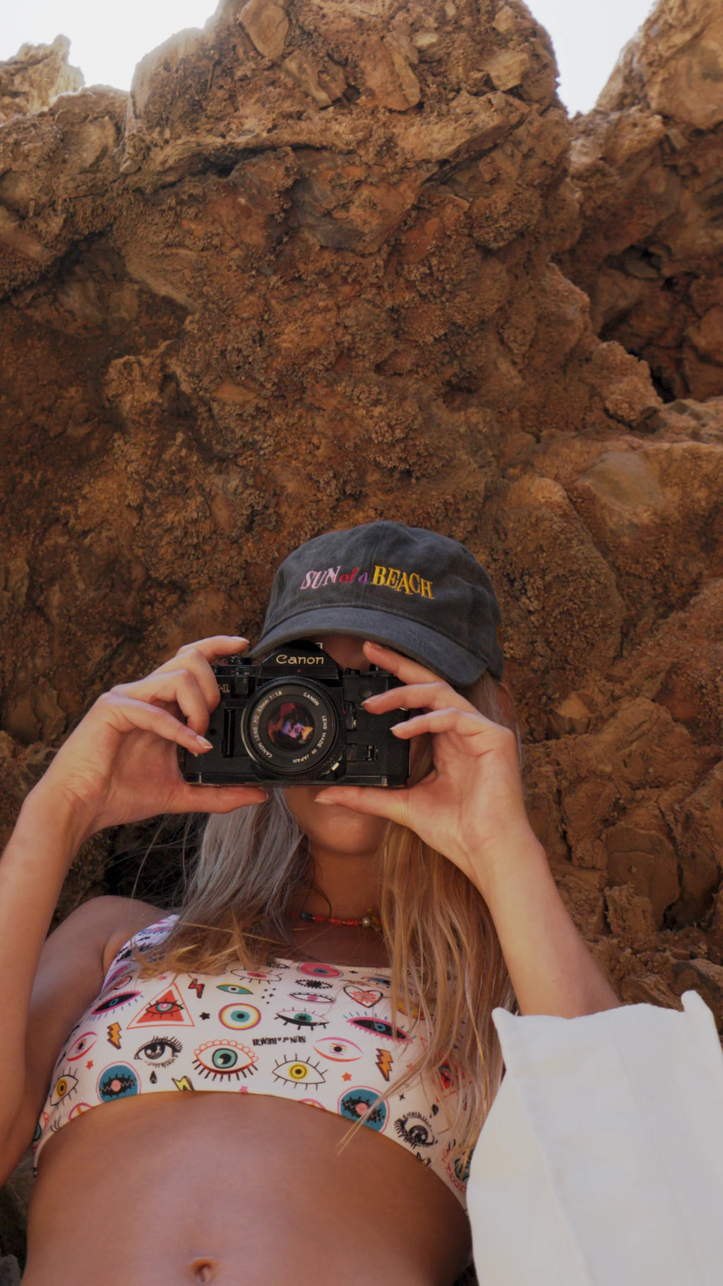 Person taking a photo with a camera against a rocky background