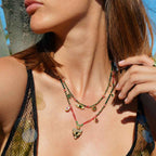 Close-up of a woman wearing a colorful beaded necklace with a blue sky background