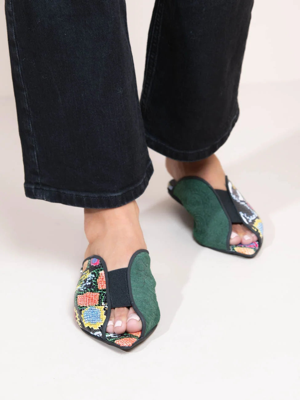 Person wearing floral-patterned green sandals on a plain background