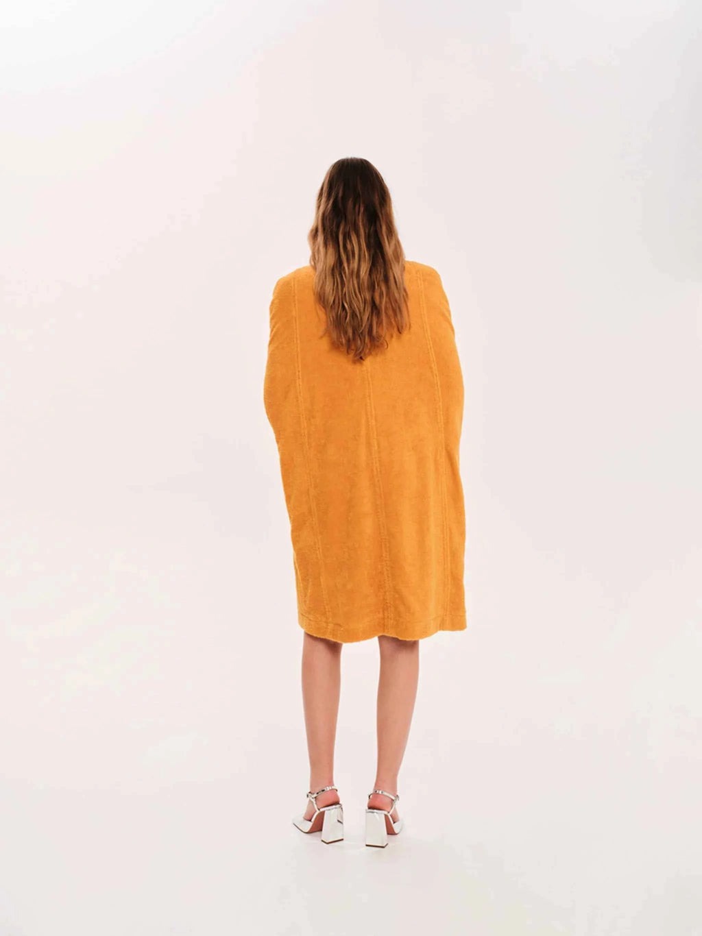 Person wearing a mustard yellow dress on a white background