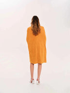Person wearing a mustard yellow dress on a white background