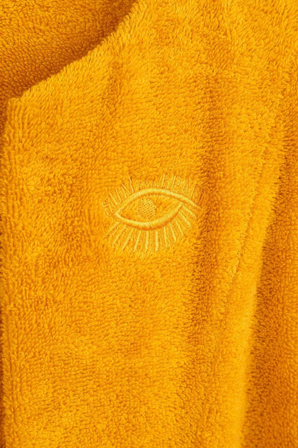 Close-up of a yellow fabric with an embroidered eye design.