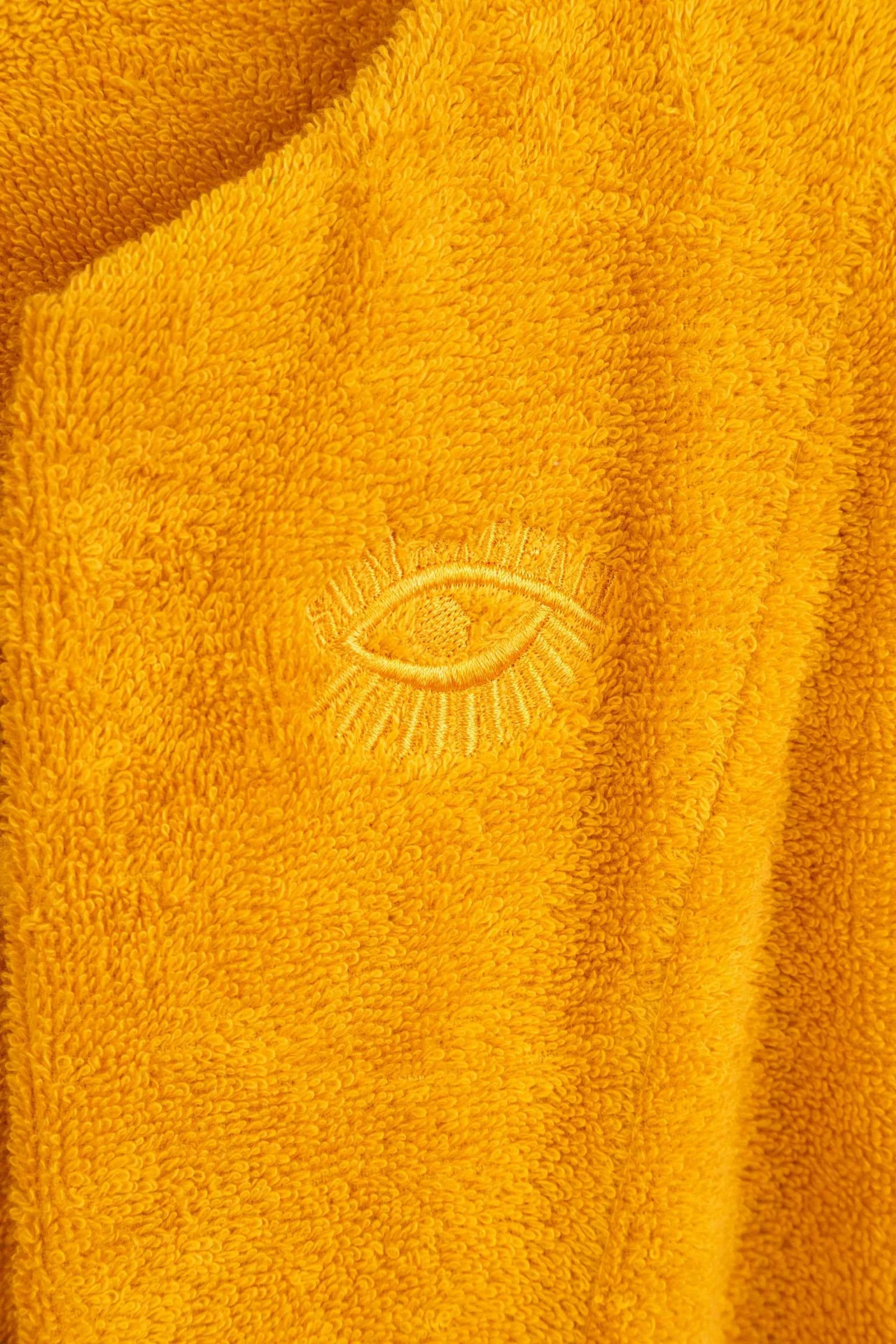 Close-up of a yellow fabric with an embroidered eye design.