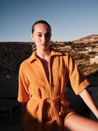 Woman wearing a mustard yellow robe with a scenic background