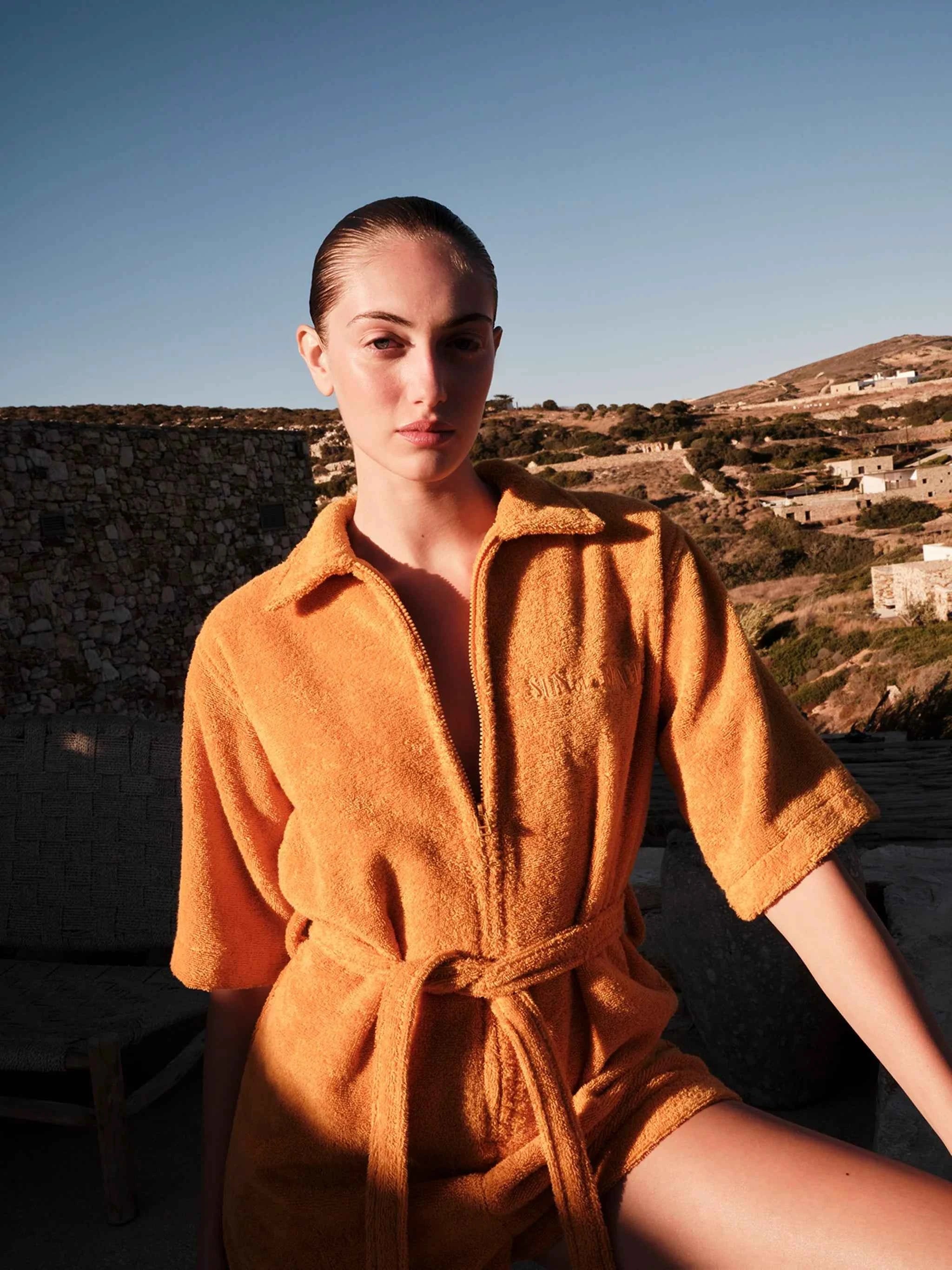 Woman wearing a mustard yellow robe with a scenic background