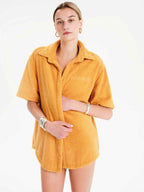 Woman wearing a mustard yellow shirt dress on a white background