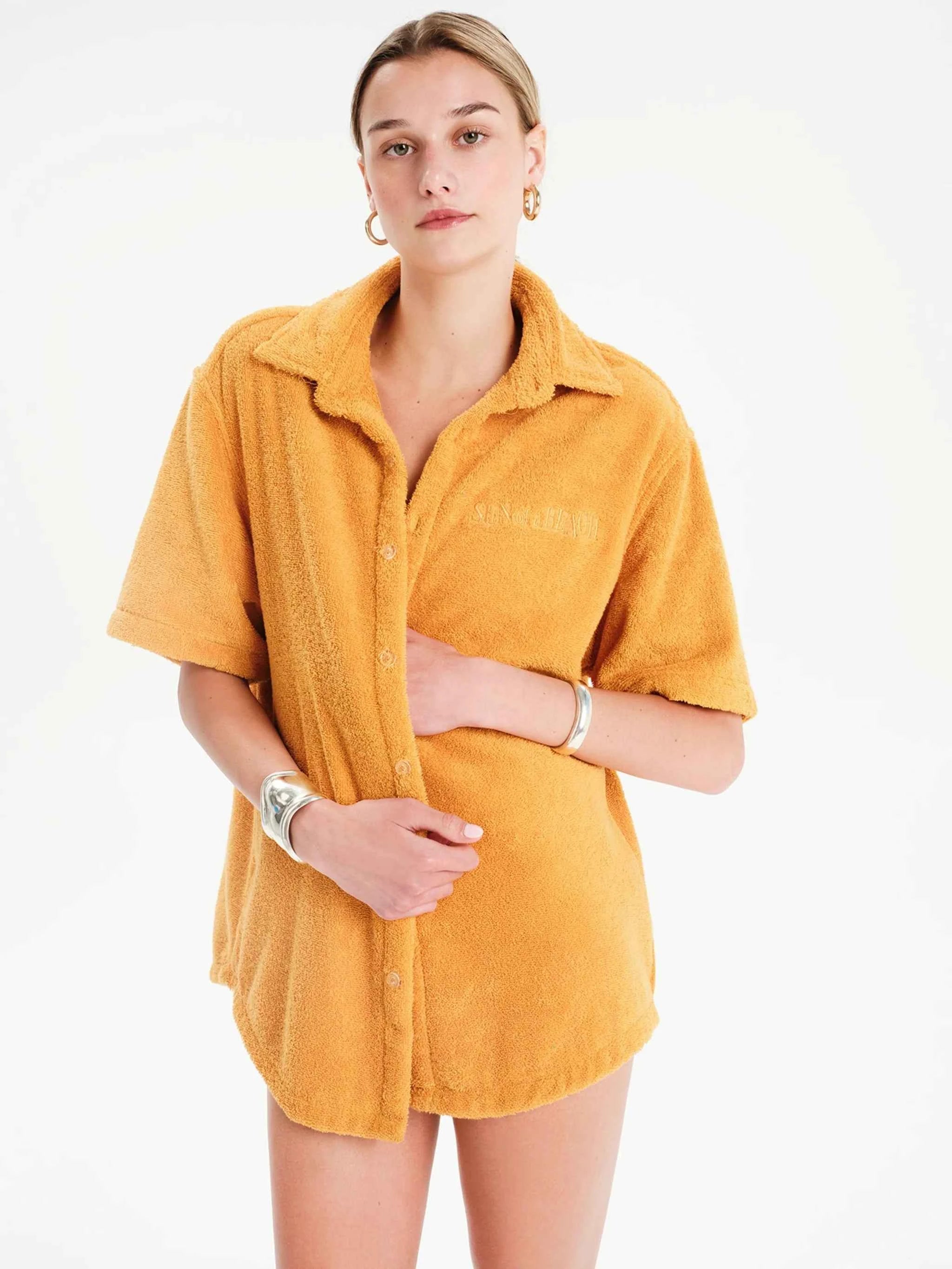 Woman wearing a mustard yellow shirt dress on a white background