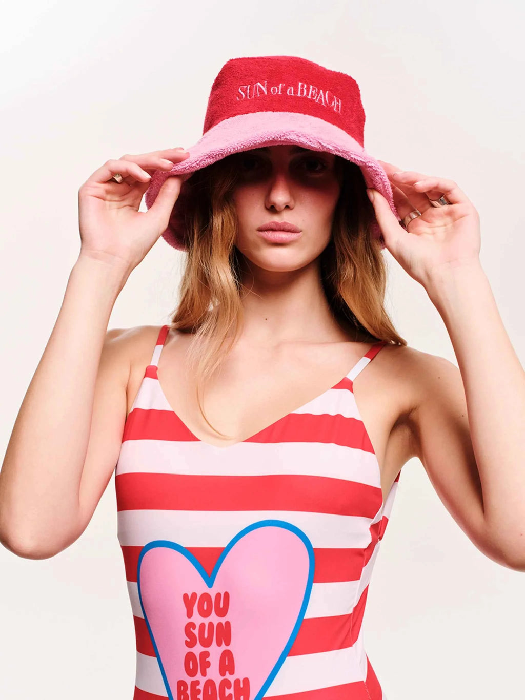 Woman wearing a red and white striped tank top with a heart design and a matching bucket hat.