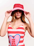 Woman wearing a red and white striped tank top with a heart design and a matching bucket hat.