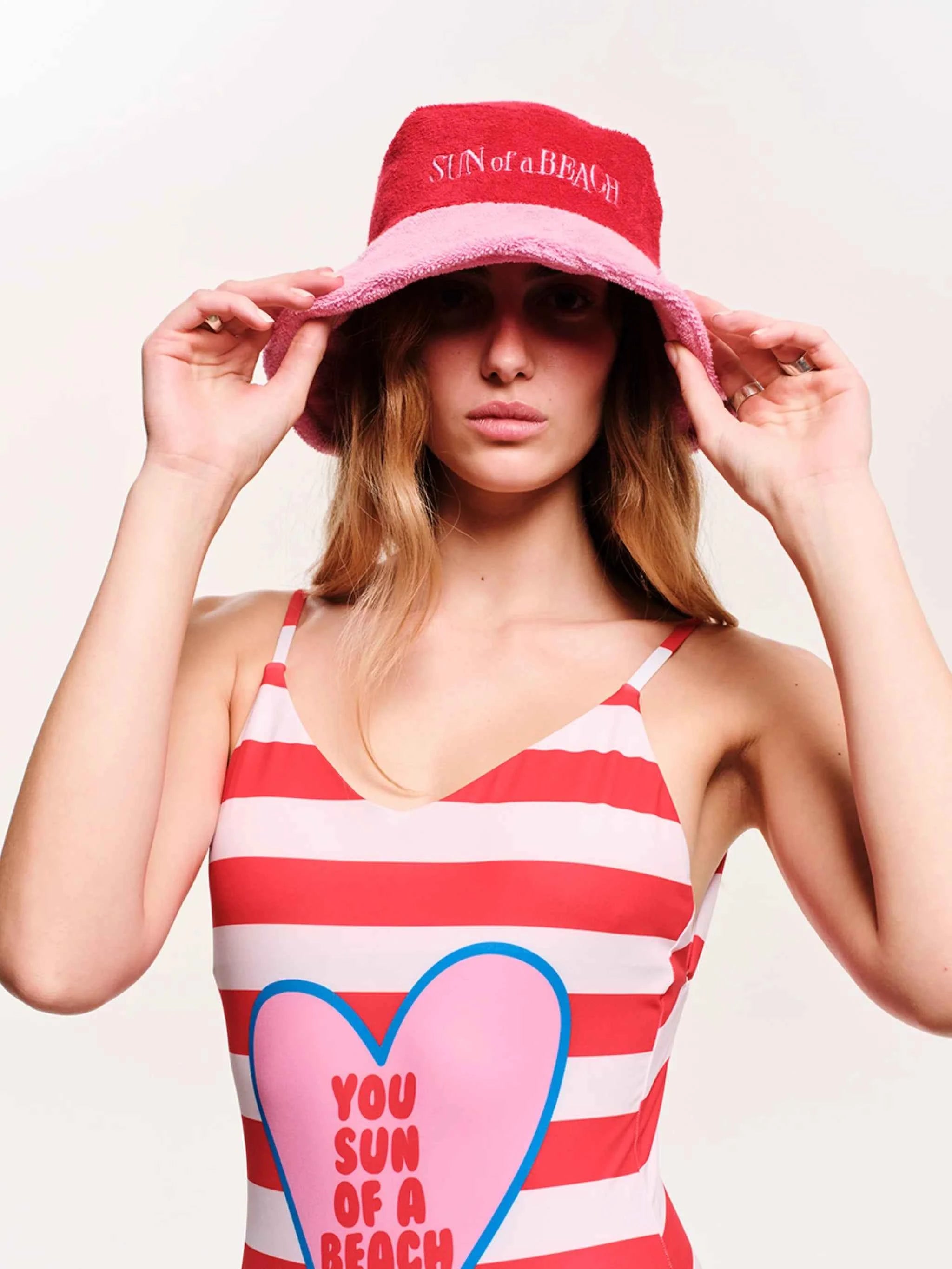 Woman wearing a red and white striped tank top with a heart design and a matching bucket hat.