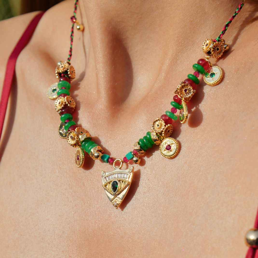 Close-up of a decorative necklace with green and red beads on a person's neck.