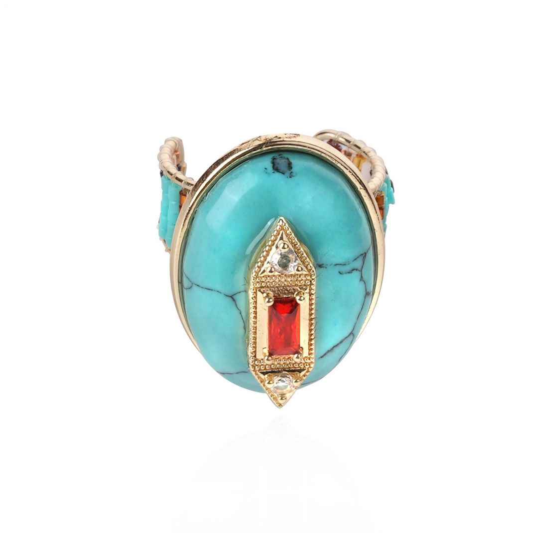 Turquoise ring with gold and red accents on a white background