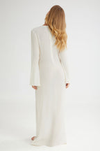 Woman wearing a long, light-colored coat against a white background