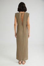 Woman wearing a long olive green dress with a cut-out back on a white background
