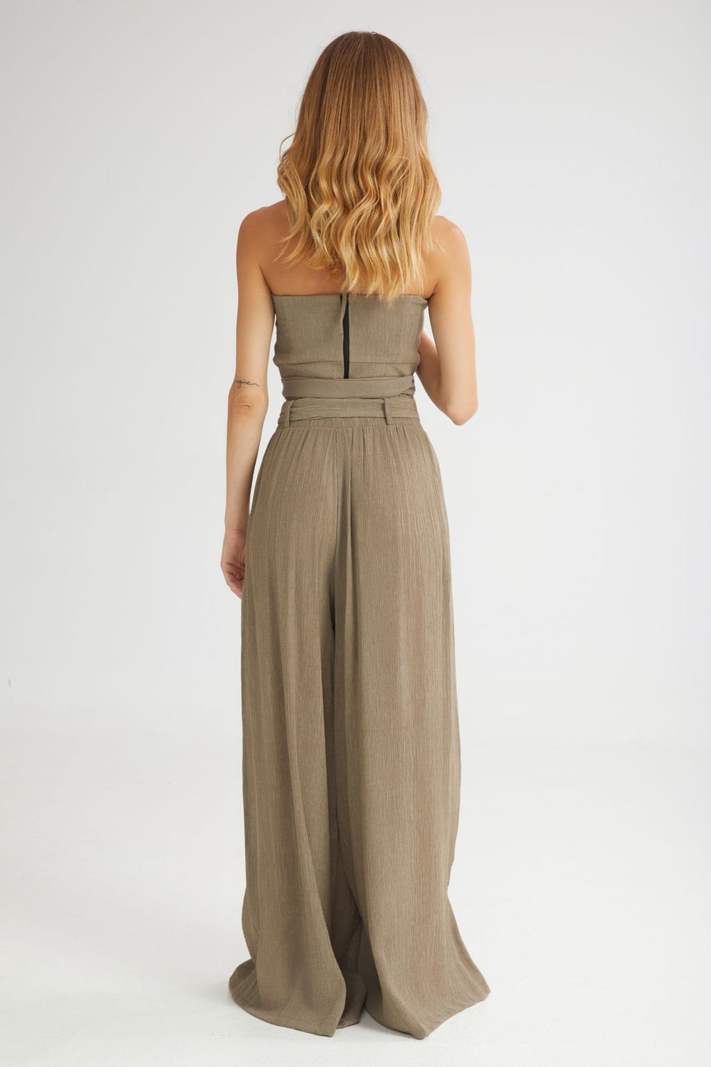 Woman wearing a strapless jumpsuit on a white background
