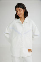 Woman wearing a white shirt with a visible brand label on a plain background