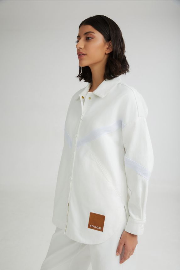 Person wearing a white shirt with a brand patch on a plain background