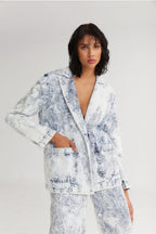 Woman wearing a light blue floral outfit against a plain background