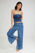 Woman wearing a blue strapless top and wide-leg jeans on a white background