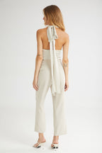 Woman wearing a white strapless top with a bow detail and matching pants on a white background