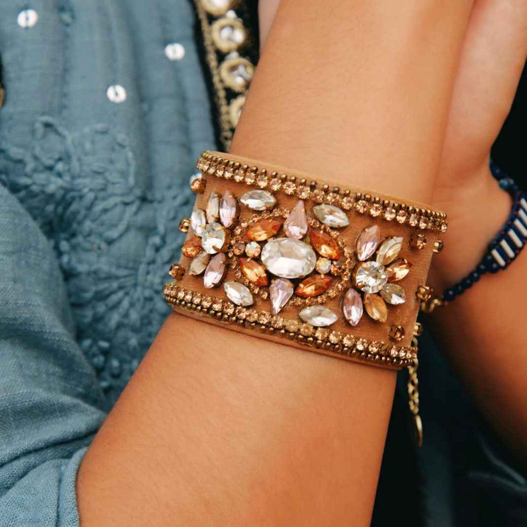 Decorative bracelet with gemstones on a wrist against a blurred background