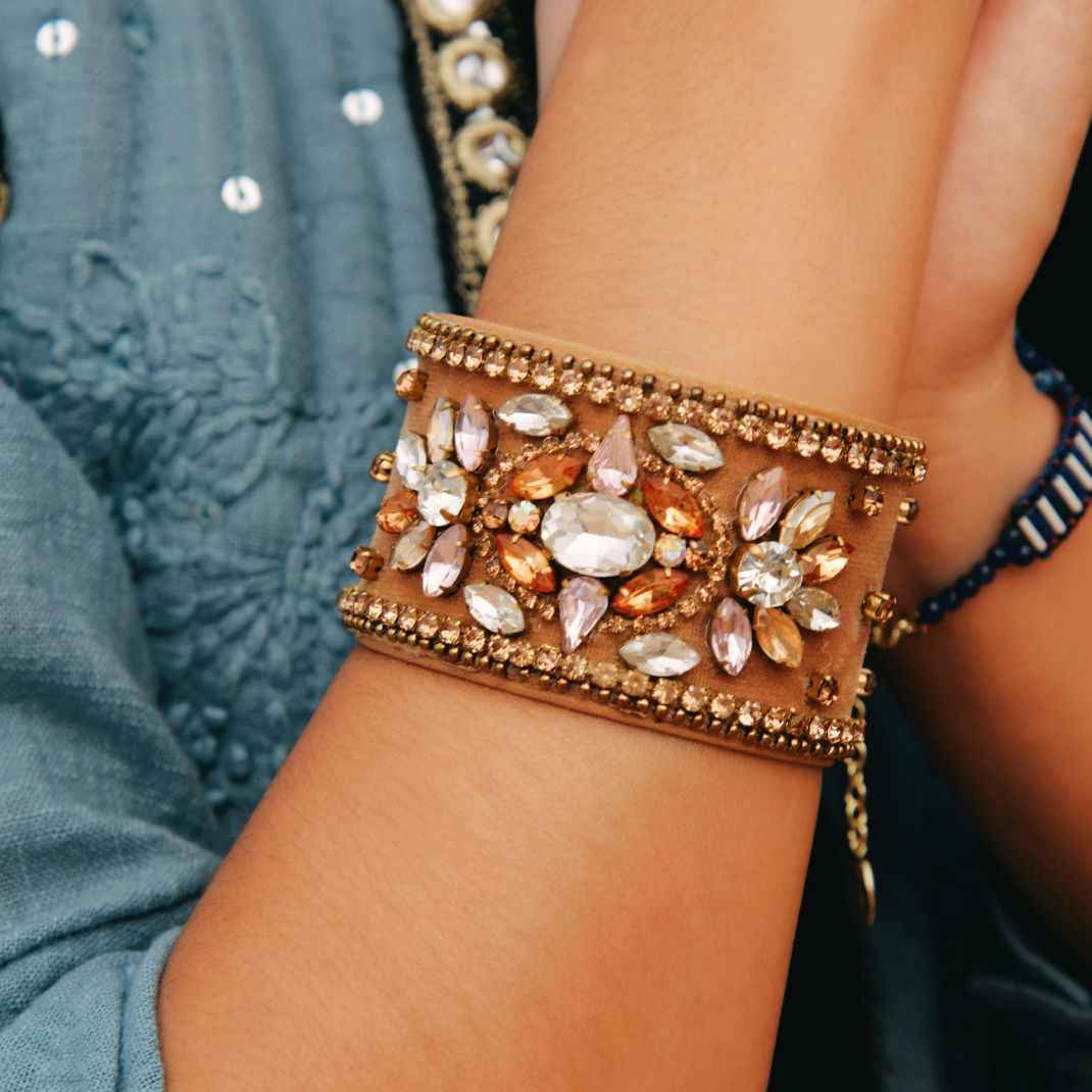 Decorative bracelet with gemstones on a wrist against a blurred background