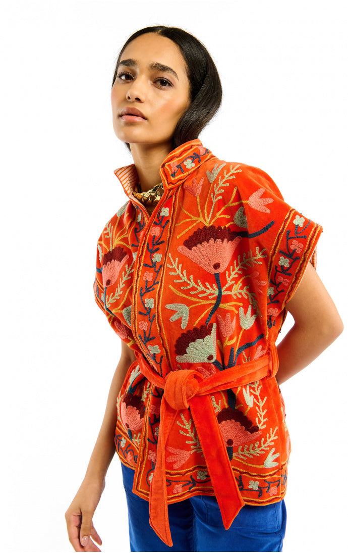 Woman wearing a vibrant orange floral-patterned top on a white background