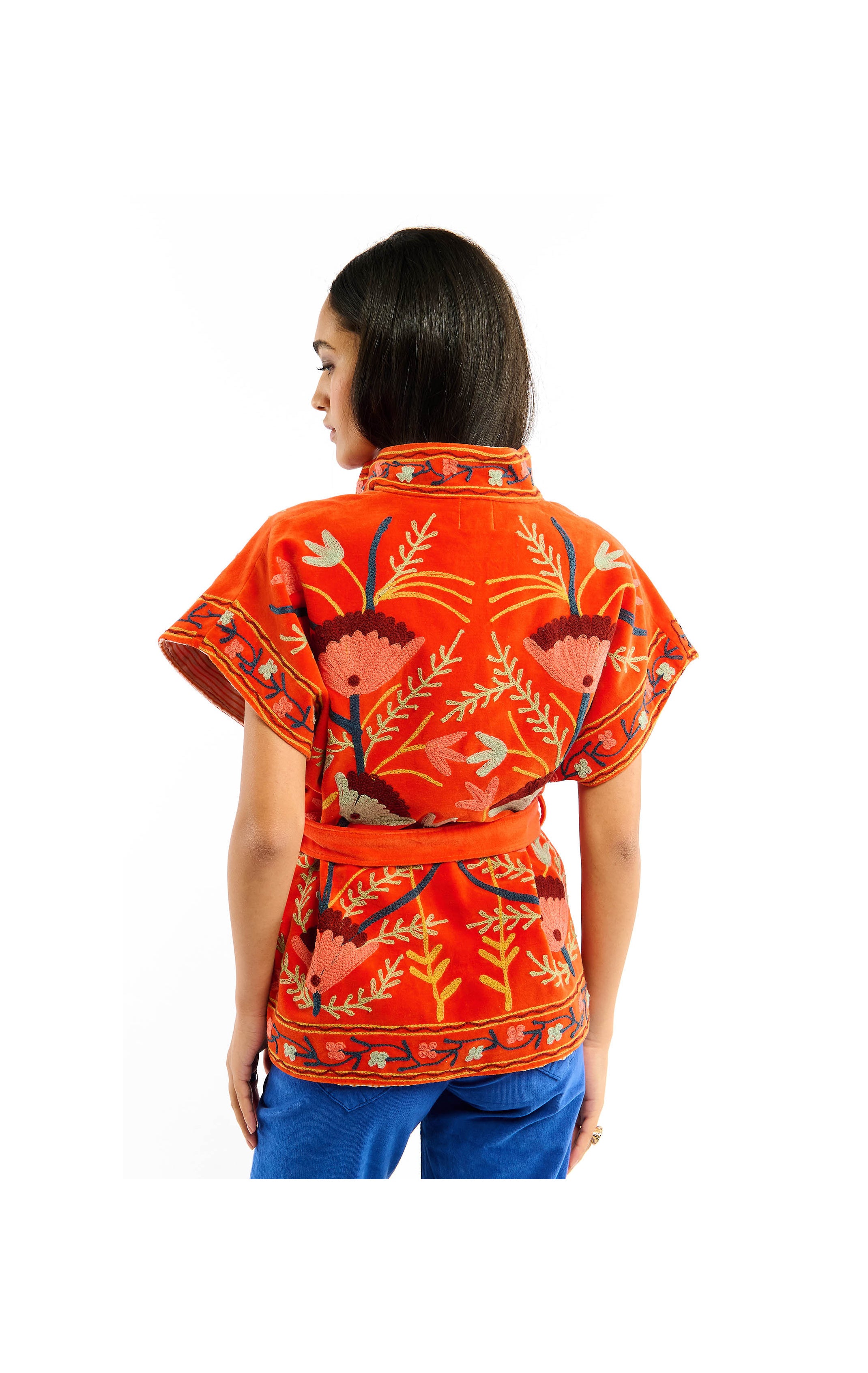 Woman wearing an orange patterned top with a white background