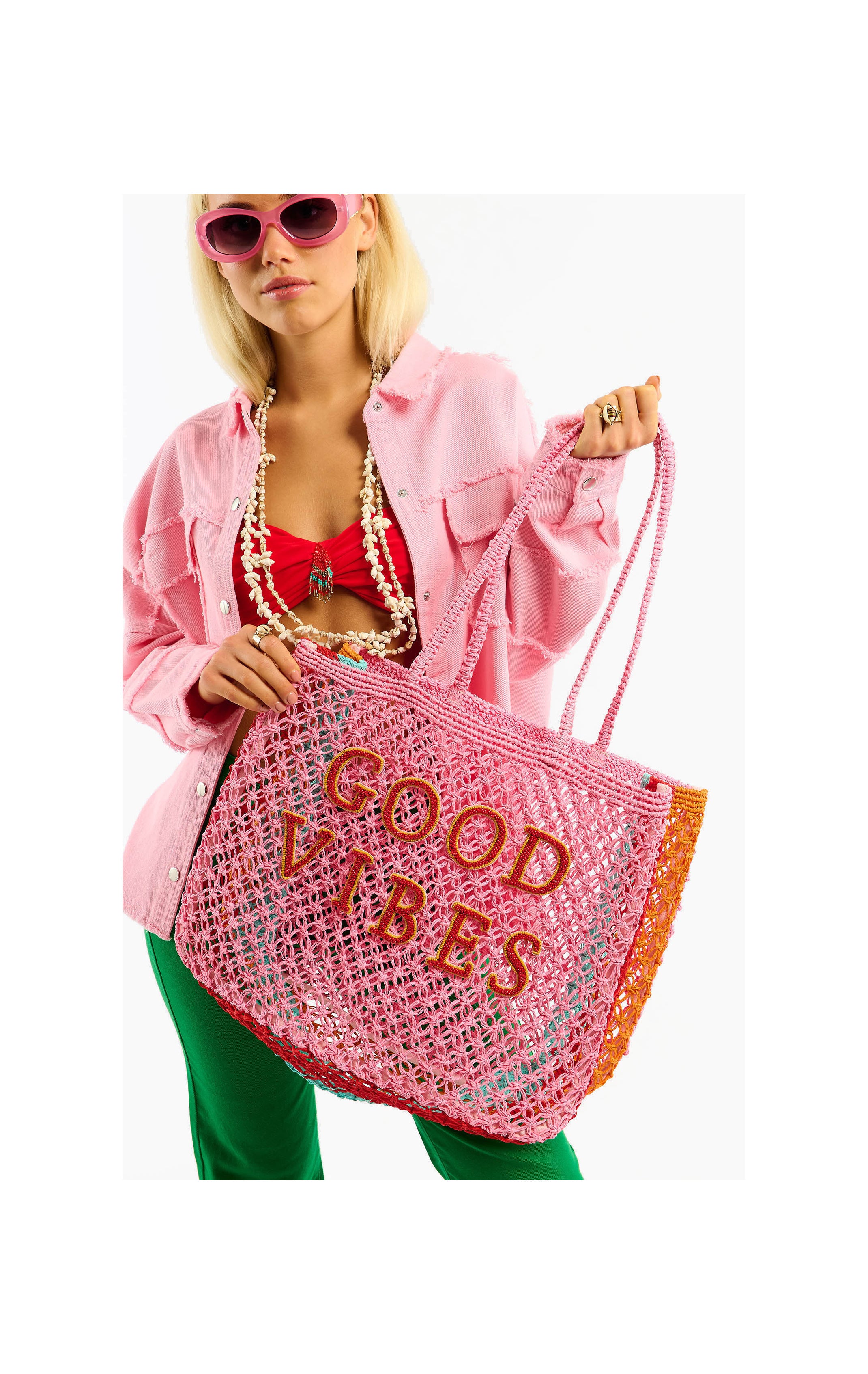 Person holding a pink mesh bag with 'Good Vibes' text against a white background