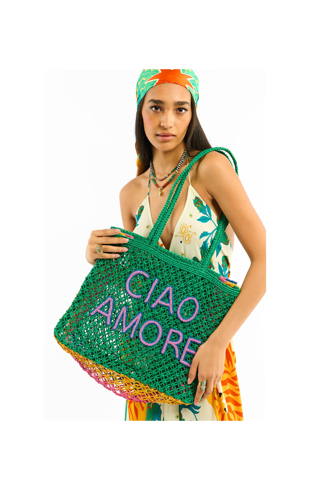 Woman holding a green woven bag with 'CIAO AMORE' text against a white background