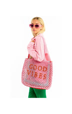Woman holding a pink tote bag with 'Good Vibes' text on a white background