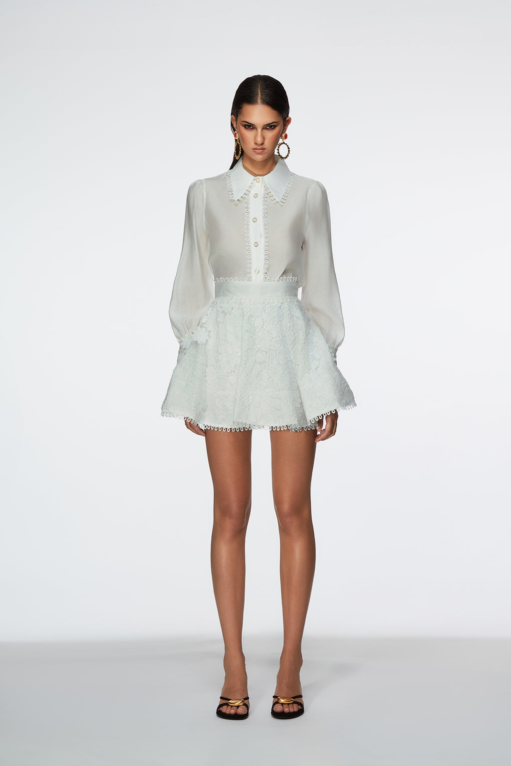 Woman wearing a white blouse and light green lace skirt on a white background