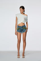 Woman wearing a white off-shoulder top and denim shorts on a white background
