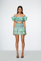 Model wearing a green and white patterned outfit on a white background
