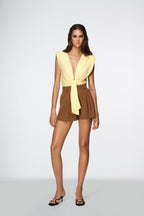 Woman wearing a yellow top and brown shorts on a white background